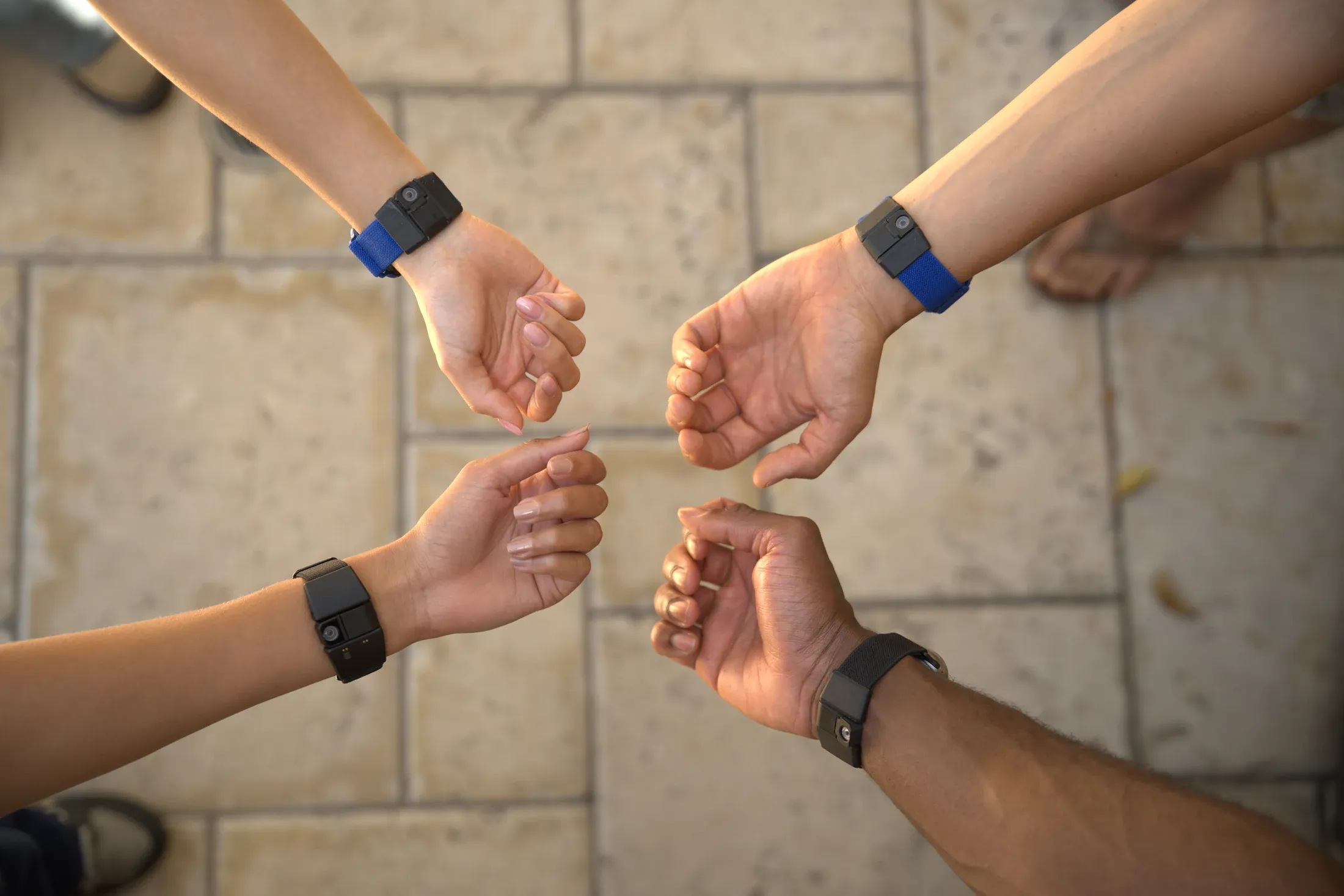 Four team members wearing Tap wristbands, fists circled together — gesture controllers ready for deployment.